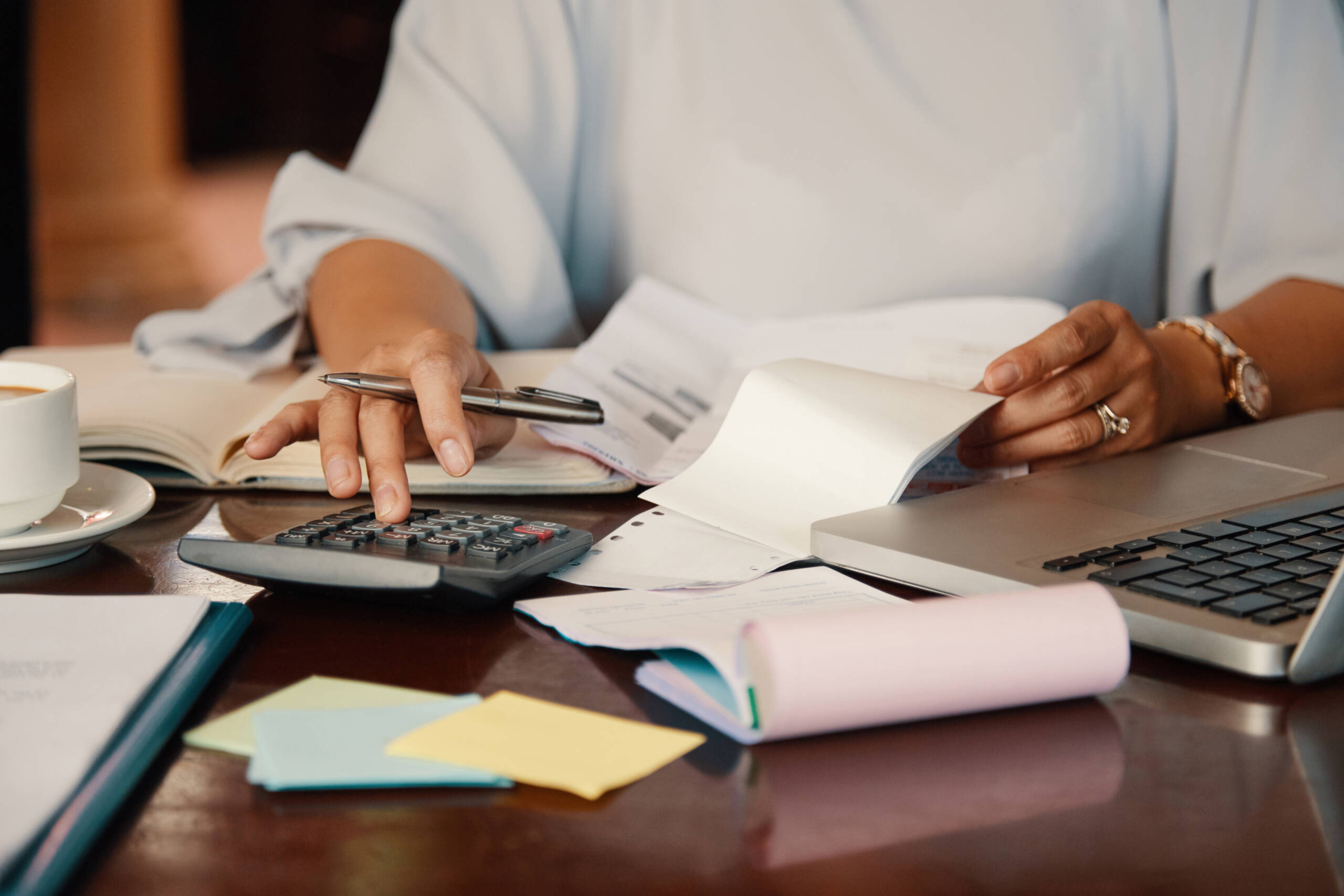 Person reviewing financial documents and using a calculator while comparing bridging loan options in Hobart.
