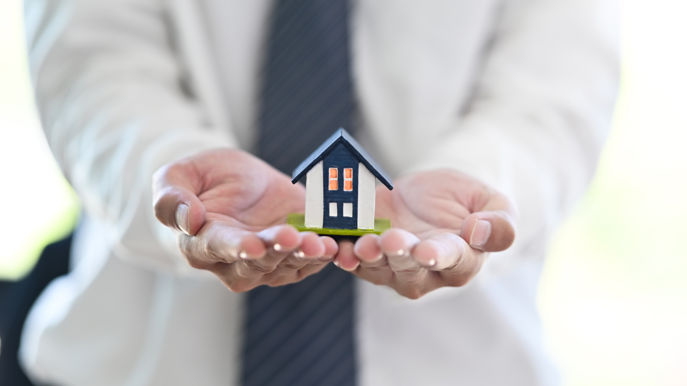 Australian bridging loan broker holding house model symbolising buy before you sell property finance.